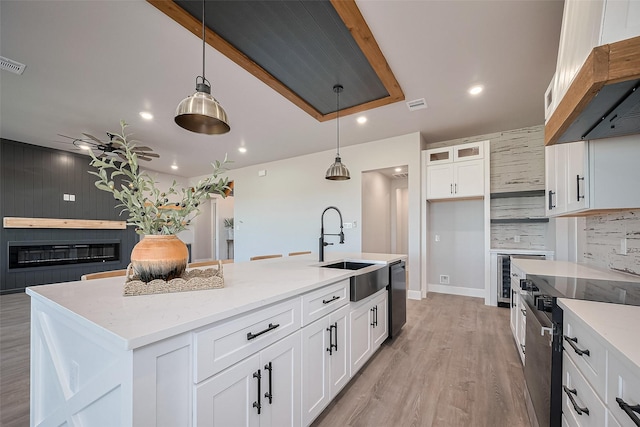kitchen featuring a sink, light stone counters, dishwasher, and under cabinet range hood
