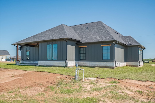 view of home's exterior featuring board and batten siding, a shingled roof, and a lawn