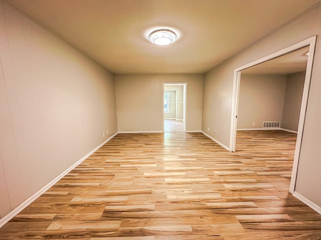 unfurnished room with visible vents, light wood-style flooring, and baseboards
