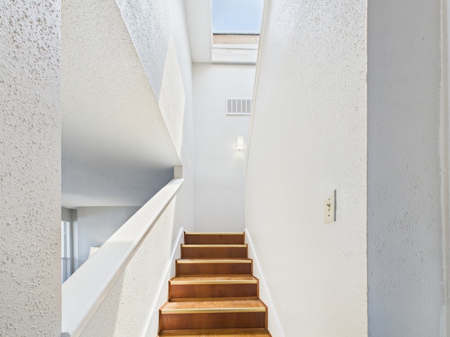 staircase with visible vents and a textured wall