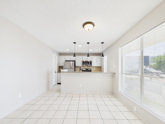 kitchen with a peninsula, white cabinets, visible vents, decorative backsplash, and stainless steel appliances