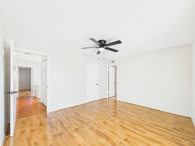 unfurnished room with light wood-style floors, visible vents, and ceiling fan
