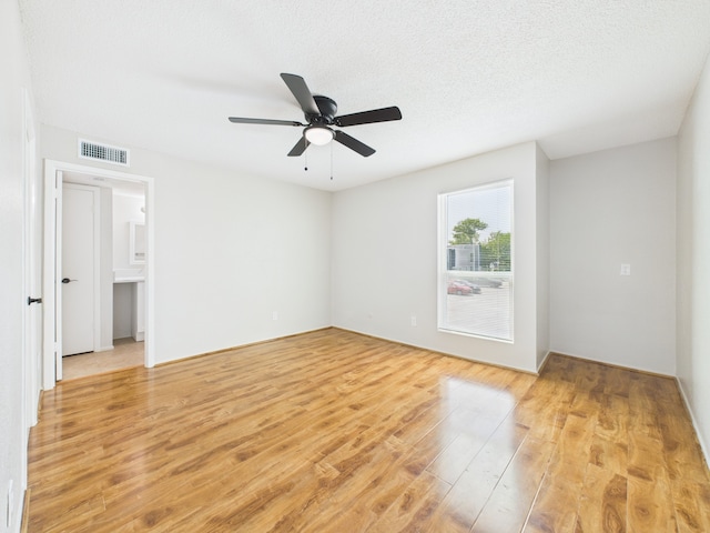 empty room with visible vents, ceiling fan, and light wood finished floors