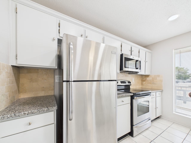 kitchen with a textured ceiling, backsplash, white cabinets, and stainless steel appliances