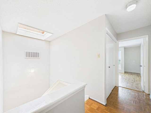 corridor with a skylight, baseboards, and visible vents