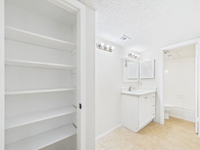 bathroom with vanity, baseboards, a textured ceiling, toilet, and visible vents