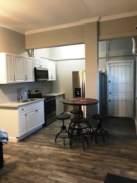 3522 Sampson St, Houston, TX 77004 - kitchen with crown molding, stainless steel appliances, dark wood-style floors, and a sink