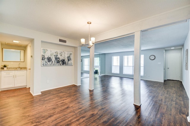 unfurnished dining area featuring visible vents, baseboards, an inviting chandelier, and dark wood finished floors