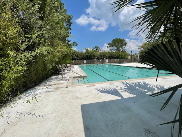 pool with a patio and fence