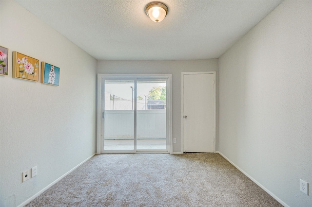spare room with a textured ceiling, carpet flooring, and baseboards