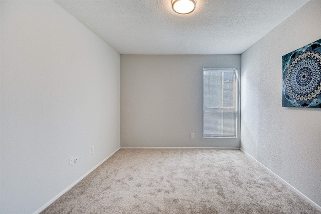 empty room featuring carpet floors, baseboards, and a textured ceiling