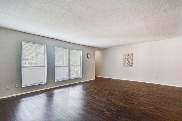 unfurnished living room with dark wood-style floors, a textured ceiling, and baseboards
