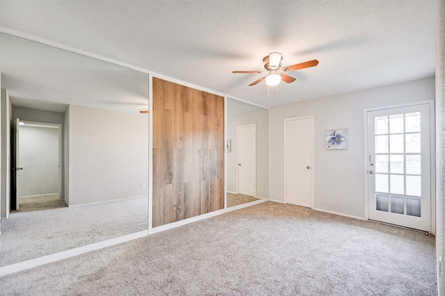 unfurnished room featuring ceiling fan, carpet flooring, baseboards, and a textured ceiling