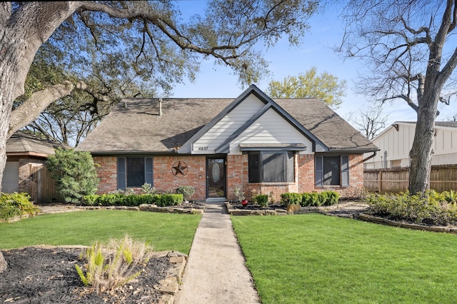 english style home featuring roof with shingles, brick siding, fence, and a front lawn