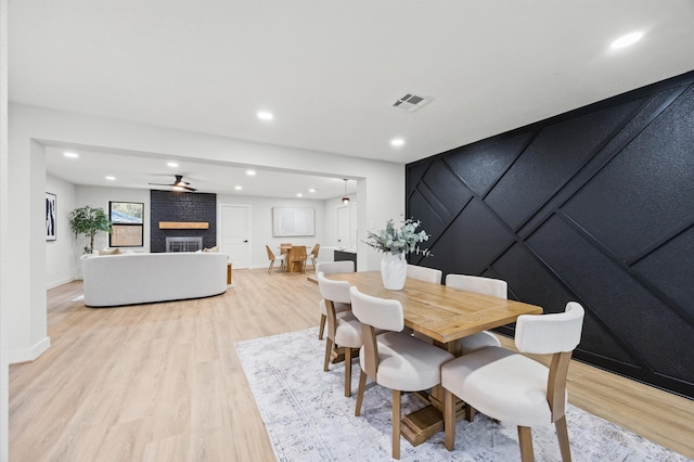 dining area featuring light wood-style flooring, a brick fireplace, visible vents, and recessed lighting