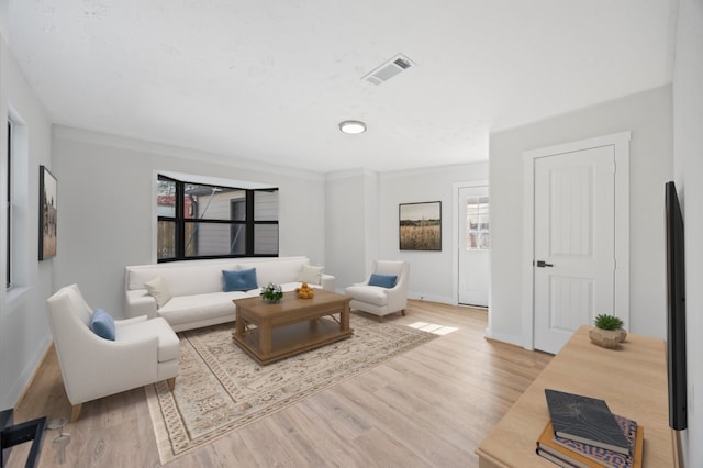 living area with visible vents, baseboards, plenty of natural light, and wood finished floors