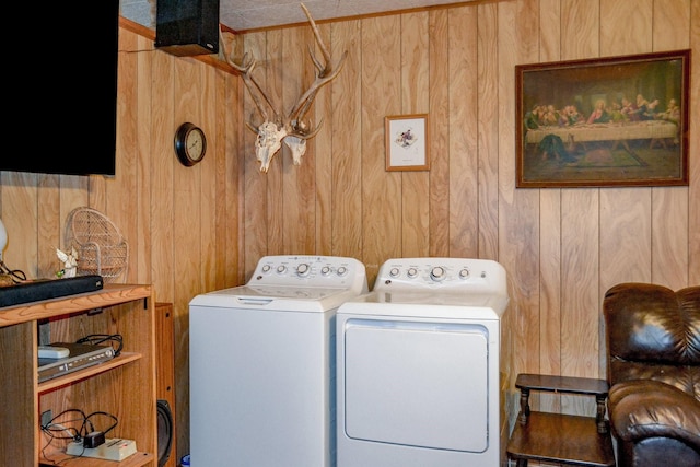 clothes washing area with wood walls and washing machine and dryer