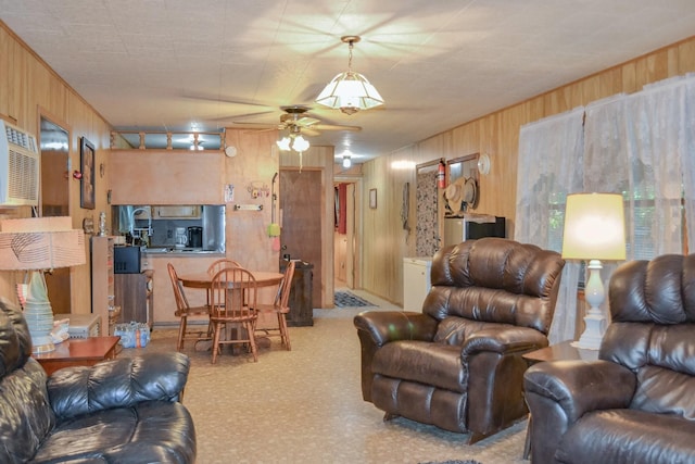 living room featuring ceiling fan, wood walls, and carpet floors