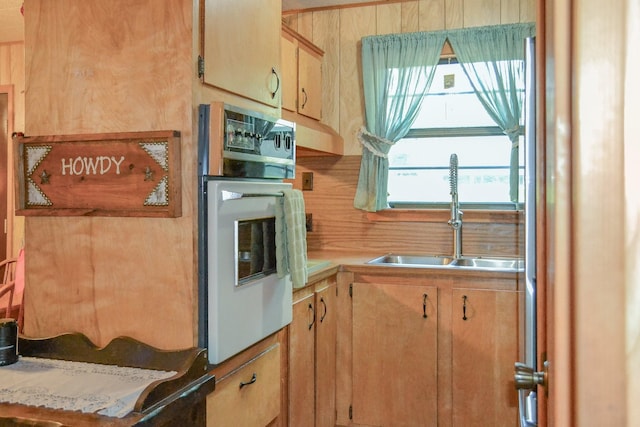 kitchen with light countertops, light brown cabinetry, a sink, and oven