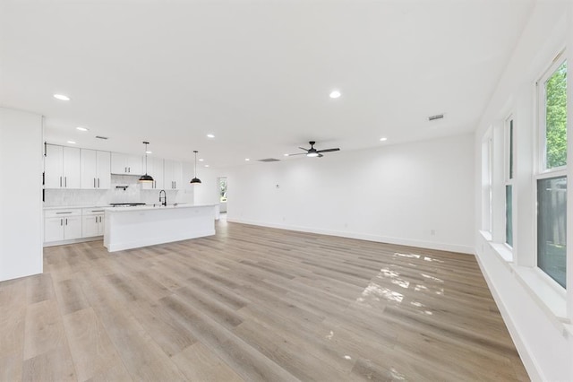 5338 Pease St, Houston, TX 77023 - unfurnished living room with baseboards, light wood-type flooring, recessed lighting, a ceiling fan, and a sink