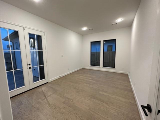 9015 Orchard Cv, Missouri City, TX 77459 - empty room featuring baseboards, recessed lighting, french doors, visible vents, and wood finished floors