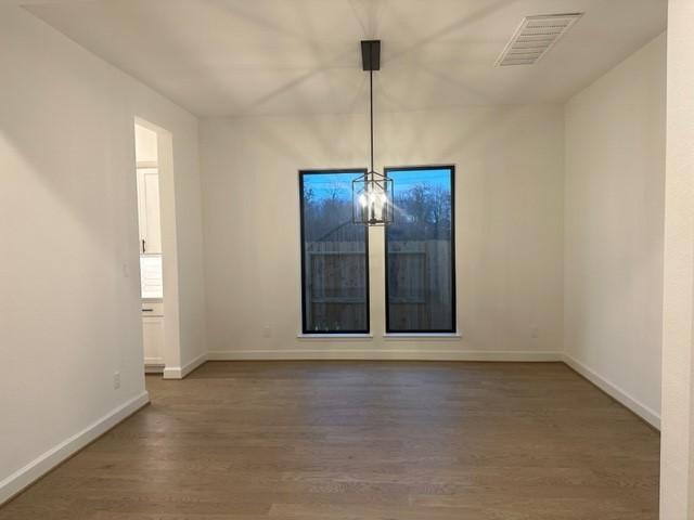 9015 Orchard Cv, Missouri City, TX 77459 - unfurnished dining area featuring a notable chandelier, visible vents, baseboards, and wood finished floors