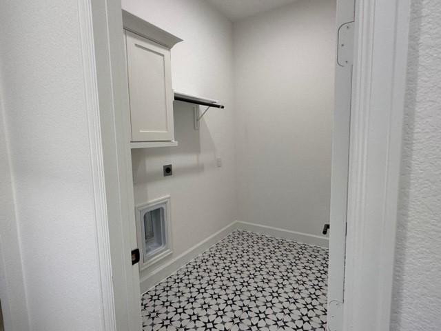 9015 Orchard Cv, Missouri City, TX 77459 - laundry area featuring cabinet space, tile patterned floors, hookup for an electric dryer, and baseboards