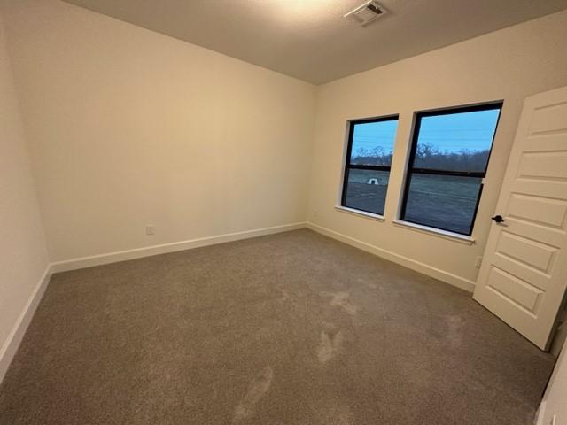 9015 Orchard Cv, Missouri City, TX 77459 - unfurnished room featuring visible vents, baseboards, and dark carpet