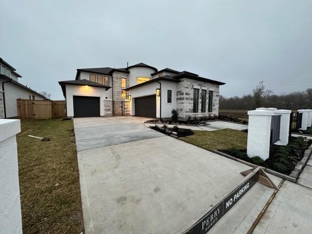 9015 Orchard Cv, Missouri City, TX 77459 - modern home with a garage, stucco siding, stone siding, fence, and concrete driveway