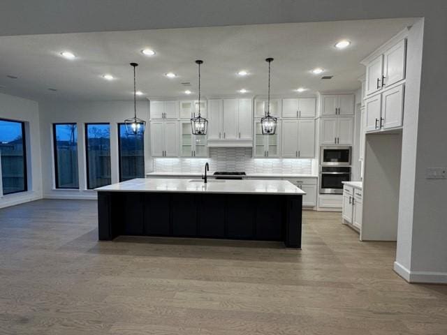 9015 Orchard Cv, Missouri City, TX 77459 - kitchen featuring baseboards, a sink, appliances with stainless steel finishes, recessed lighting, and light wood-style flooring
