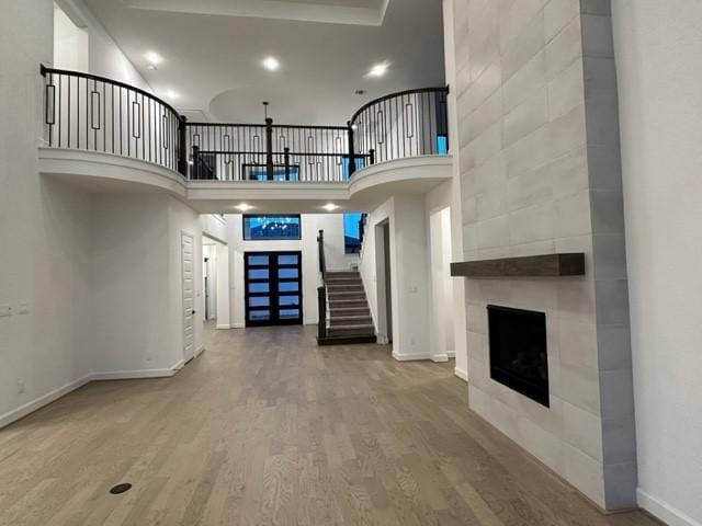 9015 Orchard Cv, Missouri City, TX 77459 - unfurnished living room with baseboards, a tiled fireplace, stairway, a high ceiling, and wood finished floors