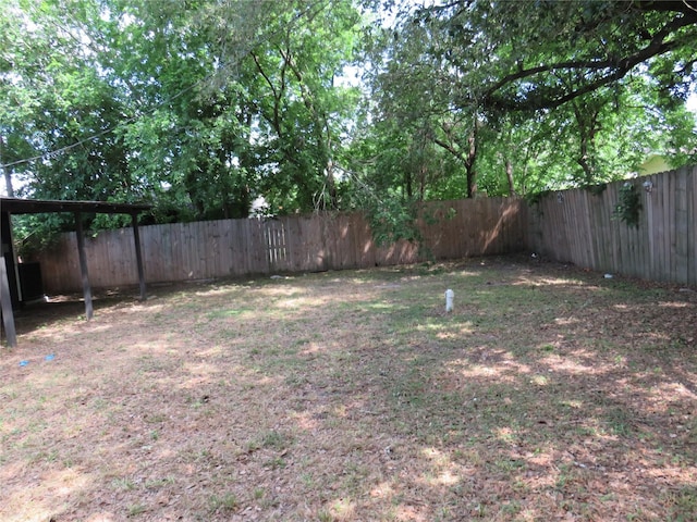 view of yard featuring a carport and a fenced backyard