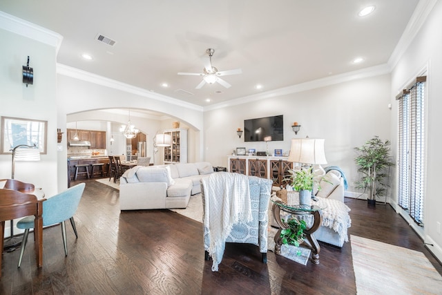 living room with arched walkways, a wealth of natural light, ceiling fan with notable chandelier, visible vents, and dark wood-type flooring