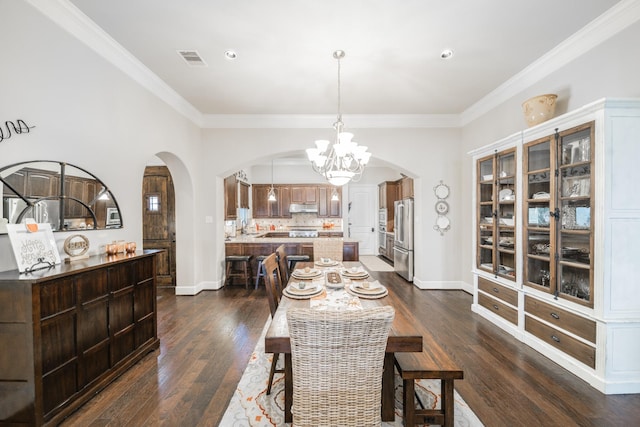 dining area with dark wood-style floors, an inviting chandelier, visible vents, ornamental molding, and arched walkways