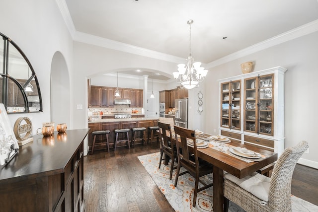 dining area with dark wood-type flooring, arched walkways, an inviting chandelier, and crown molding