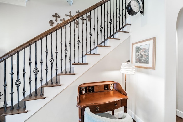 stairway with arched walkways and baseboards