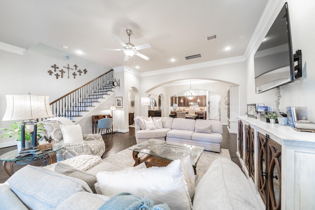 living room with arched walkways, visible vents, stairs, and wood finished floors