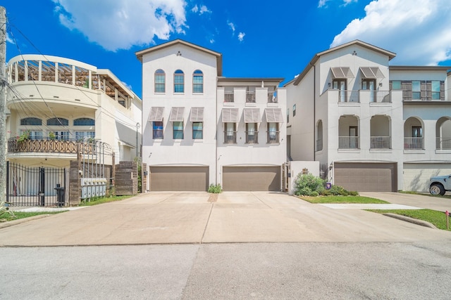 view of front of property featuring driveway, a garage, stucco siding, and fence