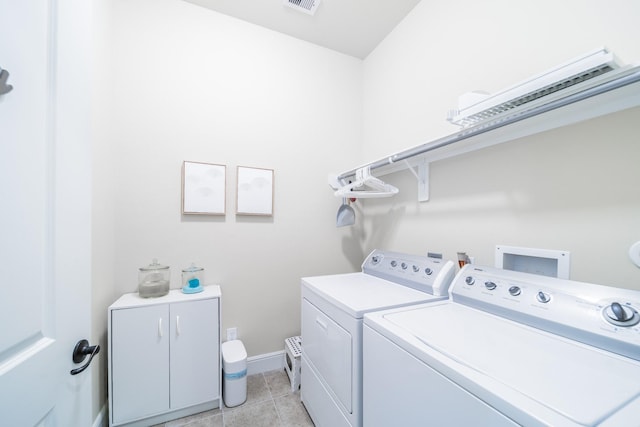 laundry area featuring baseboards, light tile patterned floors, cabinet space, and washing machine and dryer