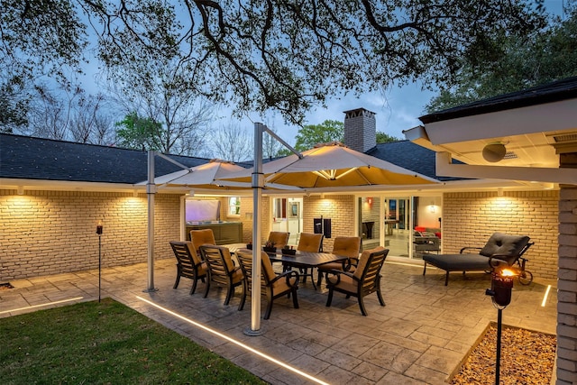 back of property with outdoor dining space, a patio area, brick siding, and a chimney