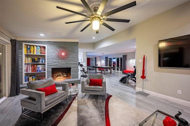 living room with baseboards, a stone fireplace, a ceiling fan, recessed lighting, and wood finished floors