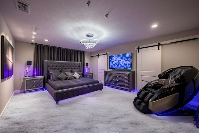 bedroom with a textured ceiling, visible vents, a barn door, carpet flooring, and baseboards
