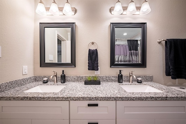 full bathroom featuring a sink, double vanity, and a textured wall