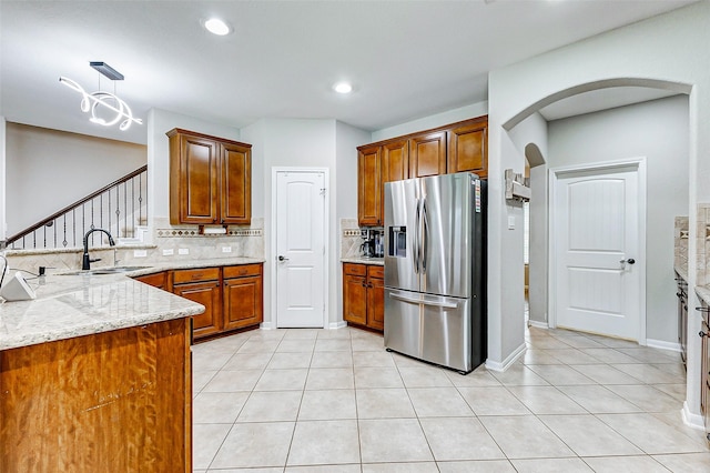 2011 Wembley Way, Rosenberg, TX 77471 - kitchen featuring a peninsula, arched walkways, stainless steel fridge with ice dispenser, a sink, and backsplash