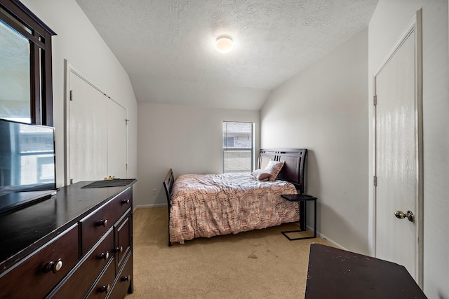 bedroom with lofted ceiling, light carpet, baseboards, and a textured ceiling