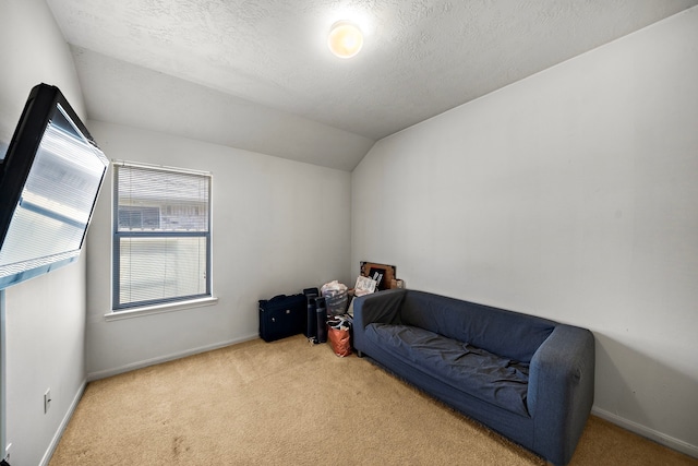 sitting room with baseboards, vaulted ceiling, carpet flooring, and a textured ceiling