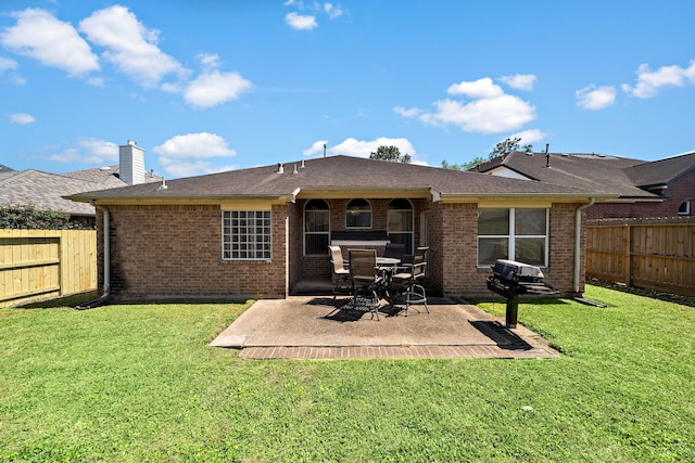 back of property featuring brick siding, a patio area, a lawn, and a fenced backyard