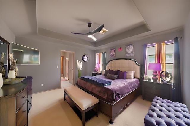 carpeted bedroom featuring a ceiling fan, visible vents, and a raised ceiling