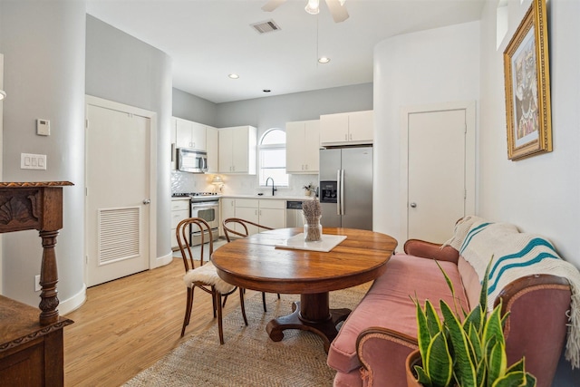 dining room featuring light wood-style floors, a ceiling fan, visible vents, and recessed lighting