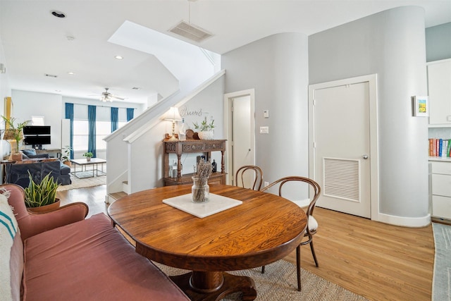 dining area featuring stairway, light wood-style flooring, visible vents, and a ceiling fan